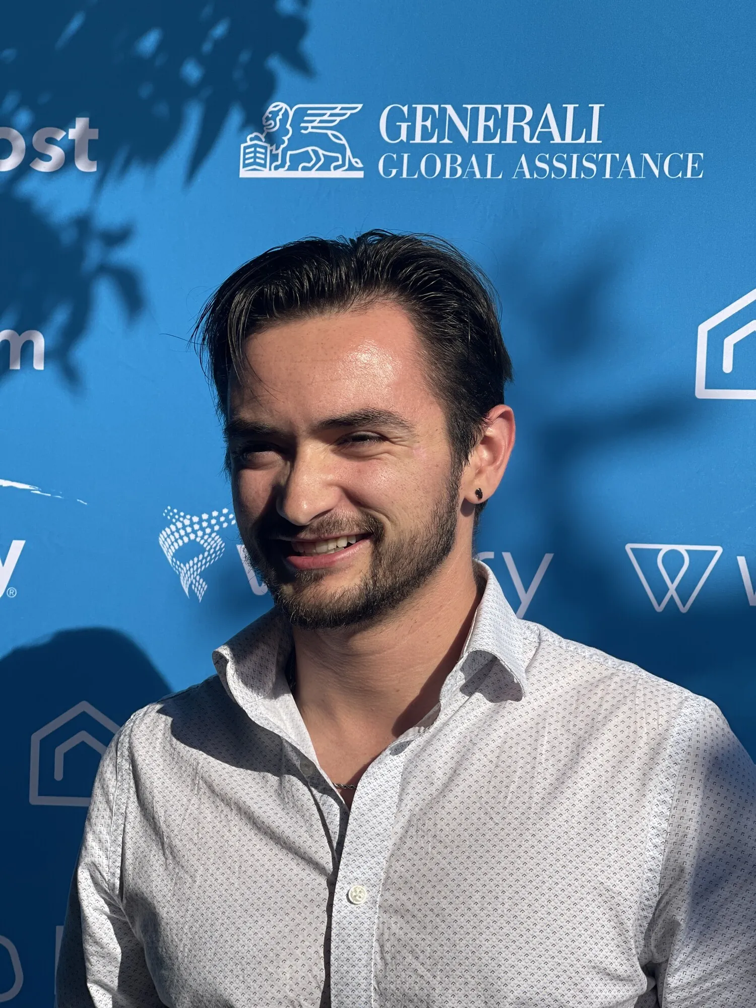 Dalton Goodyear at a short-term rental industry conference, backdropped by Guesty and travel-insurance sponsor logos.